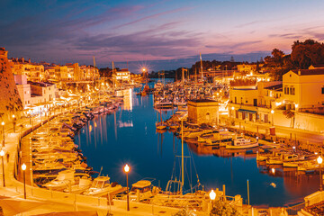 The historic tourist town of Ciutadella on the island of Menorca. Night panorama of the port and bay, the Old Town and boats bobbing on the water