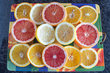 Fototapeta premium Freshly sliced citrus fruits including grapefruit, lemon, and orange arranged on a colorful cutting board for a vibrant display.