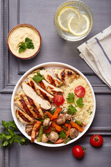 Lunch bowl with grilled chicken fillet meat, couscous, carrot, green beans and mushrooms. Top view.