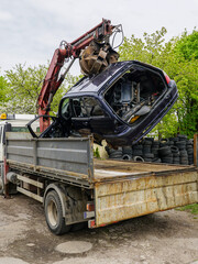 Loading an abandoned car wreck using a hydraulic loader crane mounted on a tow truck platform