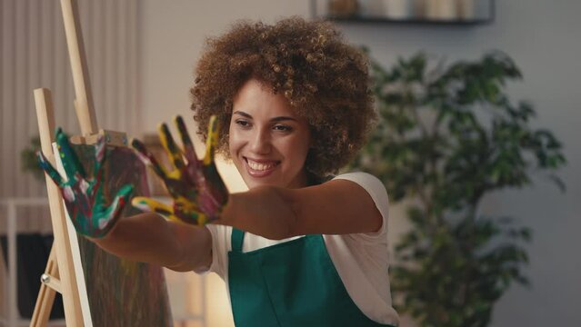 Joyful African American woman artist showing painted palms, creative hobby