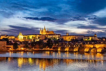Obraz premium View of Prague Castle with St. Vitus Cathedral over Lesser town named Mala Strana at sunset with the lights on, Czech Republic