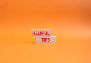 Helpful tips symbol. Wooden blocks with words Helpful tips. Beautiful orange background. Business and Helpful tips concept. Copy space.