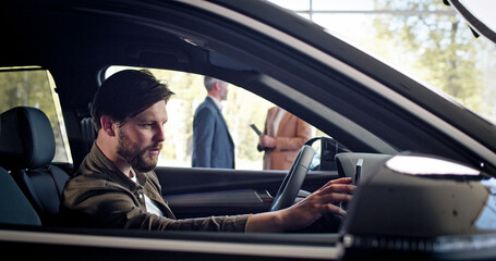 Caucasian buyer take videos on phone sitting inside new purchased automobile in auto salon....