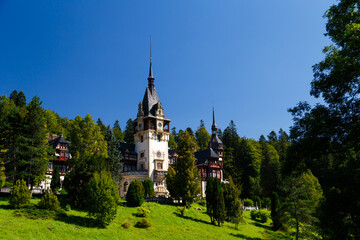 The Peles castle in the town of Sinaia, Transylvania, Carpathian Mountains, Romania, Summer time, bright sunny day with dark blue sky. The Peles castle is one of the most beautiful castles in Europe.