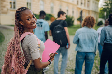 Close up of diverse female student near university building smiling.