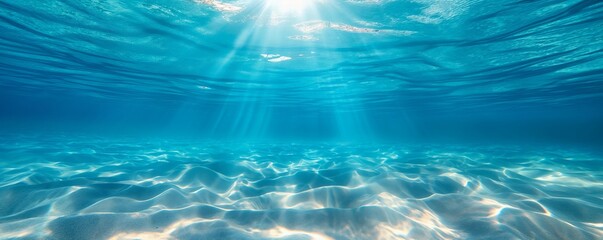 Peaceful underwater scene with light rays streaking across the sandy ocean floor