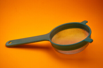 close up of a used green tea strainer on an orange background