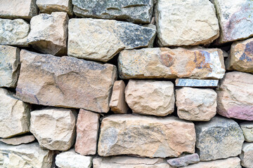 A wall made of stone blocks with a rough texture. The wall is brown and gray in color.