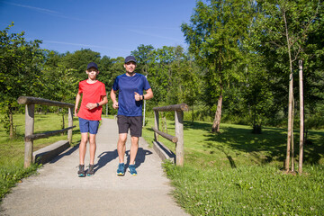 Father and son run together along a path in the park.