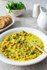 Healthy tasty lunch, soup with chickpeas and spinach, with spices and fresh herbs, with coconut milk