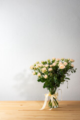 A bouquet of delicate cream roses in a glass vase, home decoration with flowers, a festive bouquet of roses for a birthday or wedding