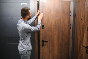 A young man chooses metal front door in the hardware store