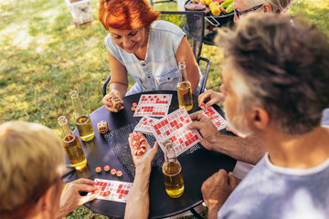 Group of elderly retired people playing bingo outside. Drinking beer and enjoying some time outside.
