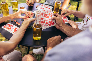 Group of elderly retired people playing bingo outside. Drinking beer and enjoying some time outside.