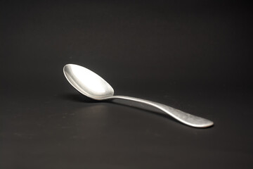plain tablespoon made of stainless steel on black background