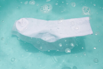 Cleaning dirty socks in basin of soapy water
