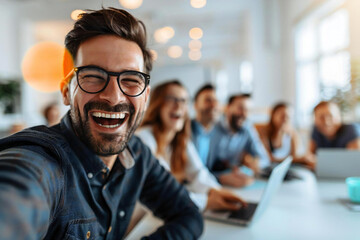 Obraz premium Business people in smart casual attire with glasses laughing in a conference room with white and light gray decor, with a blurred foreground object.
