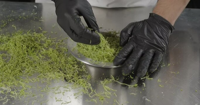 Kunefe or kunafa traditional Turkish dessert. Pastry chef tamp kataifi dough with pistachios in the copper plate with hands. Arabic sweets. Middle eastern national food desserts