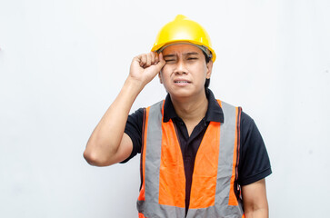 Asian male construction worker in hardhat and orange vest looks sad with crying gesture. stressed overworked concept. workers' insurance concept.
