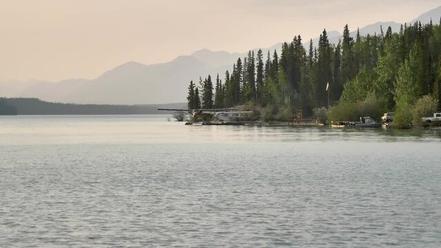 Bush planes parked on the lake shore along the Alaska Highway. Flightseeing tours by seaplanes in North America