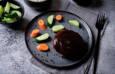 Asian meet hamburger with sauce, rice and vegetables in a plate