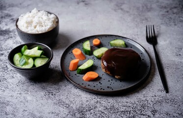 Asian meet hamburger with sauce, rice and vegetables in a plate