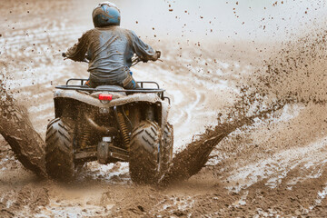 Obraz premium A man is riding an ATV through a muddy field, negotiating the challenging terrain with skill