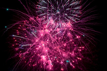 Fototapeta premium Pink fireworks explode in the night sky. Selective focus.