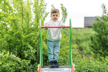 Happy toddler playing on colorful slide. Playground.
