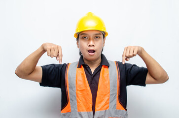 A happy, surprised asian construction worker in black shirt and yellow safety helmet pointing a finger and presenting something ads.	
