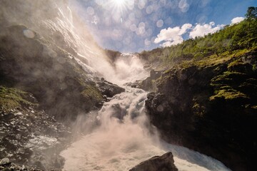 Magnificent waterfall cascading down a rocky landscape with sunlight
