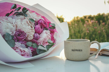 Cup with text BLESSED and open Bible in the garden, good morning