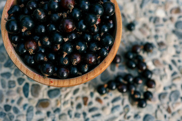 Black currant in a wooden bowl on nature