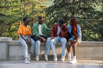 Fototapeta premium Group of African friends together outside. Company of black students provide friendly support to upset guy. Classmates listen to buddy experiencing problems with studies and romantic relationships. 