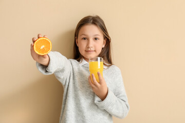 Cute little girl with glass of juice and orange on beige background