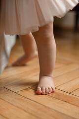 Baby  barefoot standing on wooden  floor