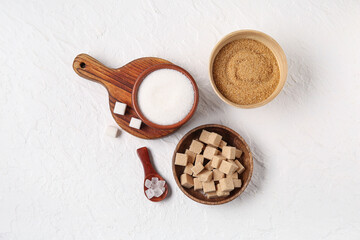 Bowls different types of sugar on white background