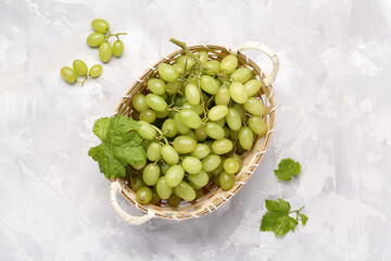 Top view of basket with white grapes on color background