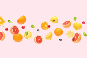 Summer fruit, grapefruit, oranges, lemons ,berries, cherries flying on a pink background. Summer food concept.