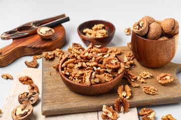 Bowls with tasty walnuts on grey background