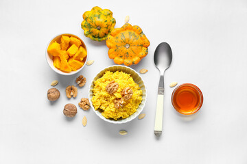Bowls of tasty millet porridge with pumpkin and ingredients on grey background