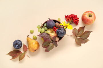 Bowl with different fresh fruits on beige background