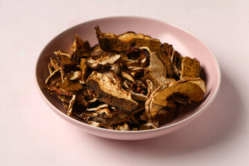 Bowl with tasty dried mushrooms on white background
