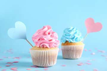 Delicious cupcakes with blue and pink frosting on color background. Gender reveal party concept