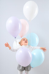 Cute little girl with beautiful balloons on grey background