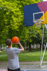 Teenager Shooting Basketball on Outdoor Court in Summer