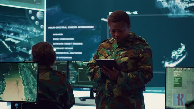 Woman sergeant major working on deployment of electronic warfare tools to disrupt enemy communications. Female army soldier with camouflage uniform operating on high tech gear. Camera A.