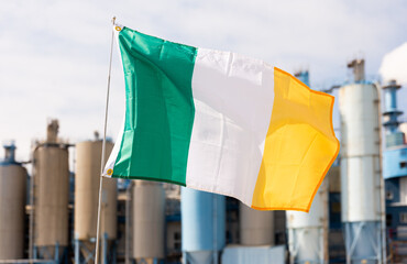 Large flag of Ireland waving against background of factory