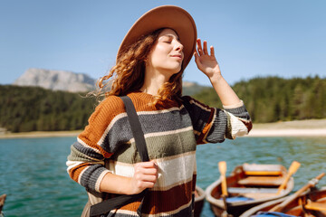 Young woman walking on wooden pier at lake in mountains, enjoying view. Active lifestyle